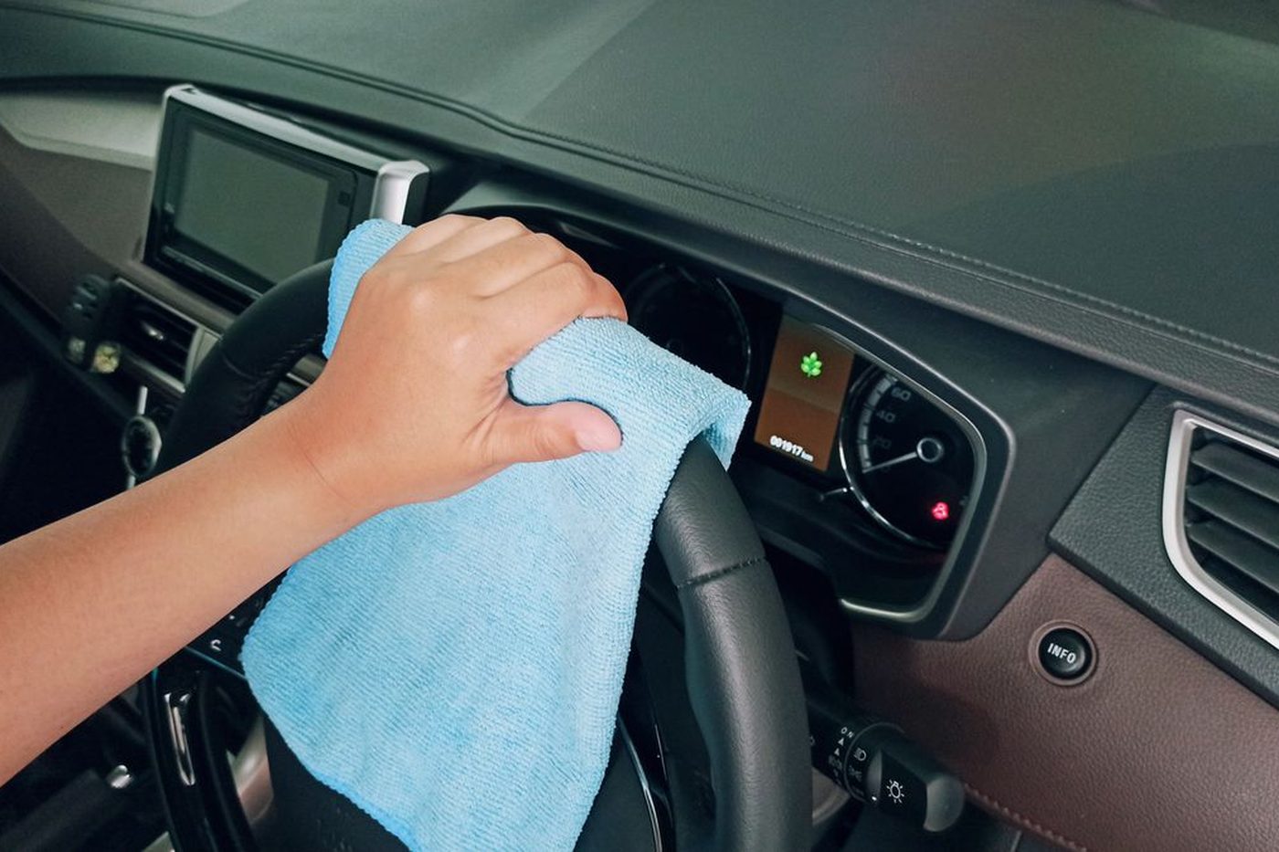 A dashboard being cleaned by hand with a microfibre cloth