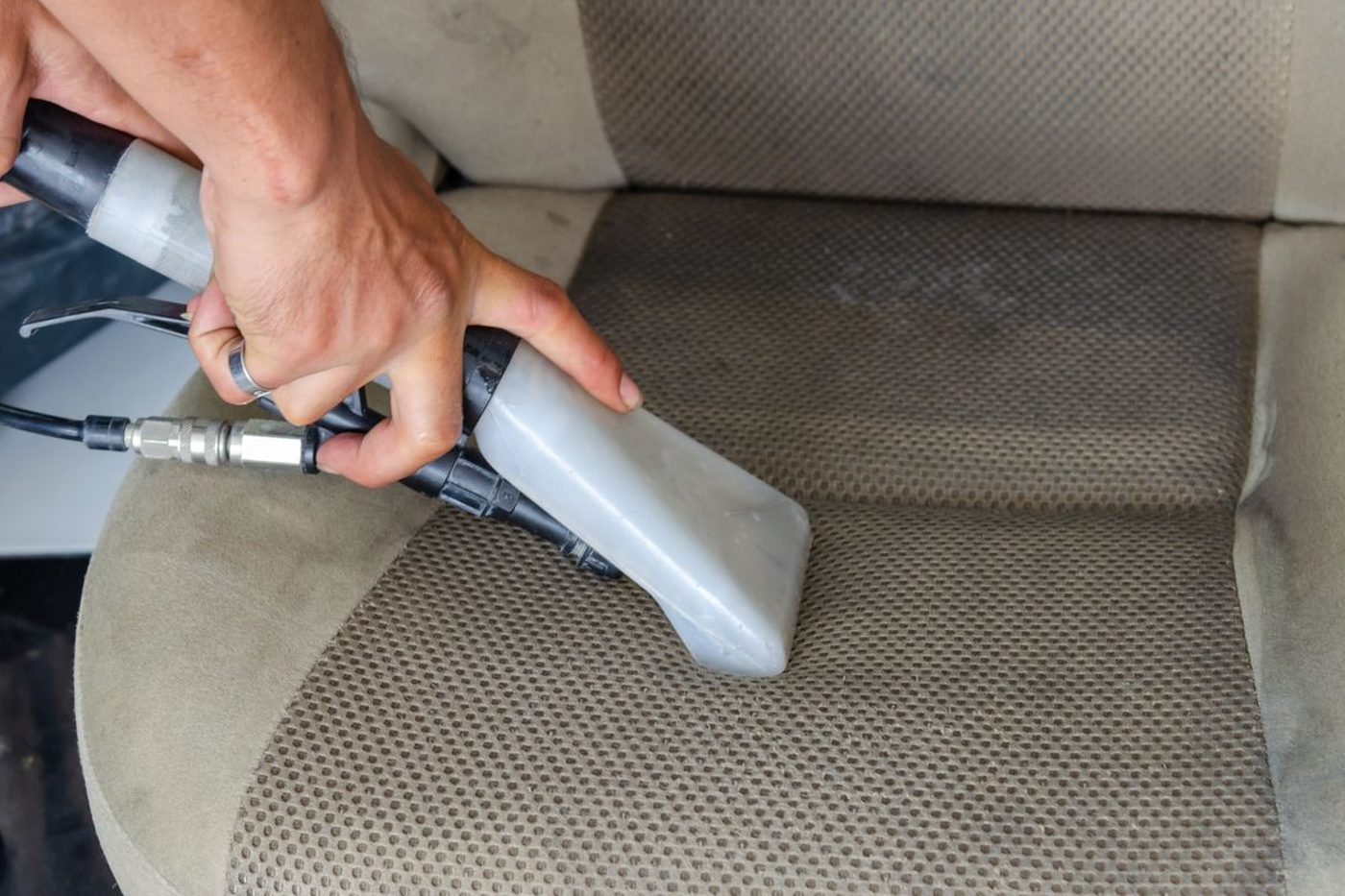 A car seat being vacuumed into the seams