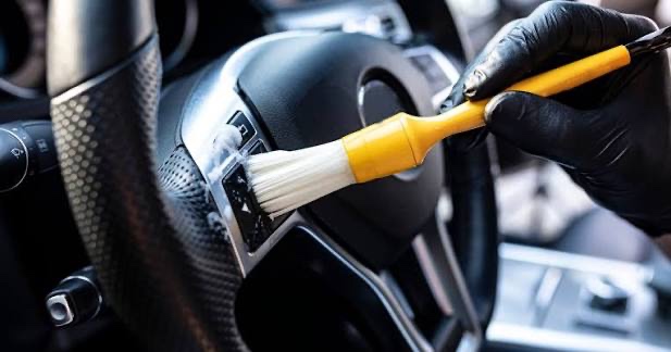 A detailing brush lifting dust out of the switchgear on a steering wheel
